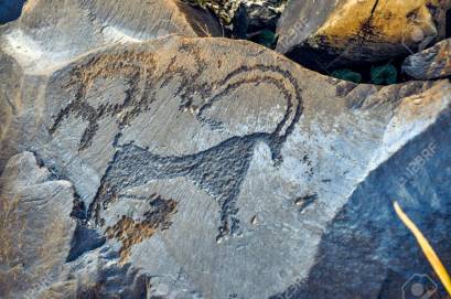 Close up of ancient pictograms engraved on rock on Saimaluu Tash site in Kyrgyzstan